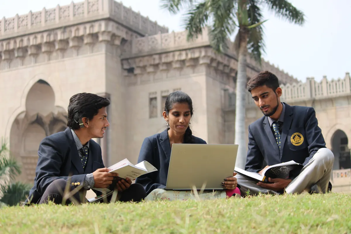 Three students studying together on a campus lawn