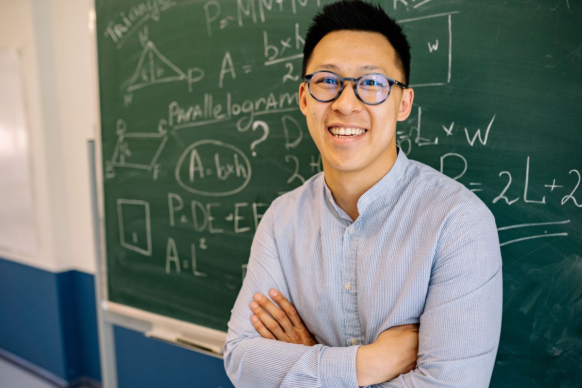 A teacher at a blackboard covered in geometry working